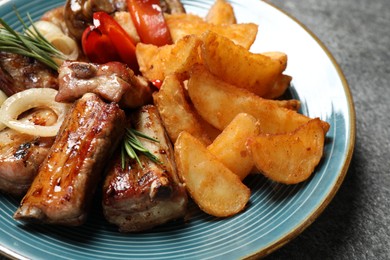 Photo of Delicious grilled ribs and garnish on grey table, closeup