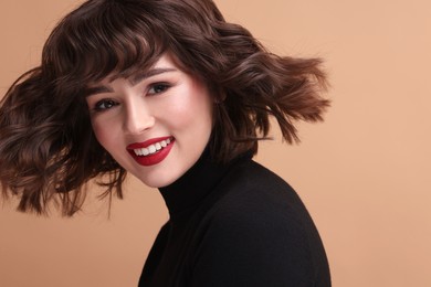 Portrait of beautiful young woman with wavy hairstyle on beige background