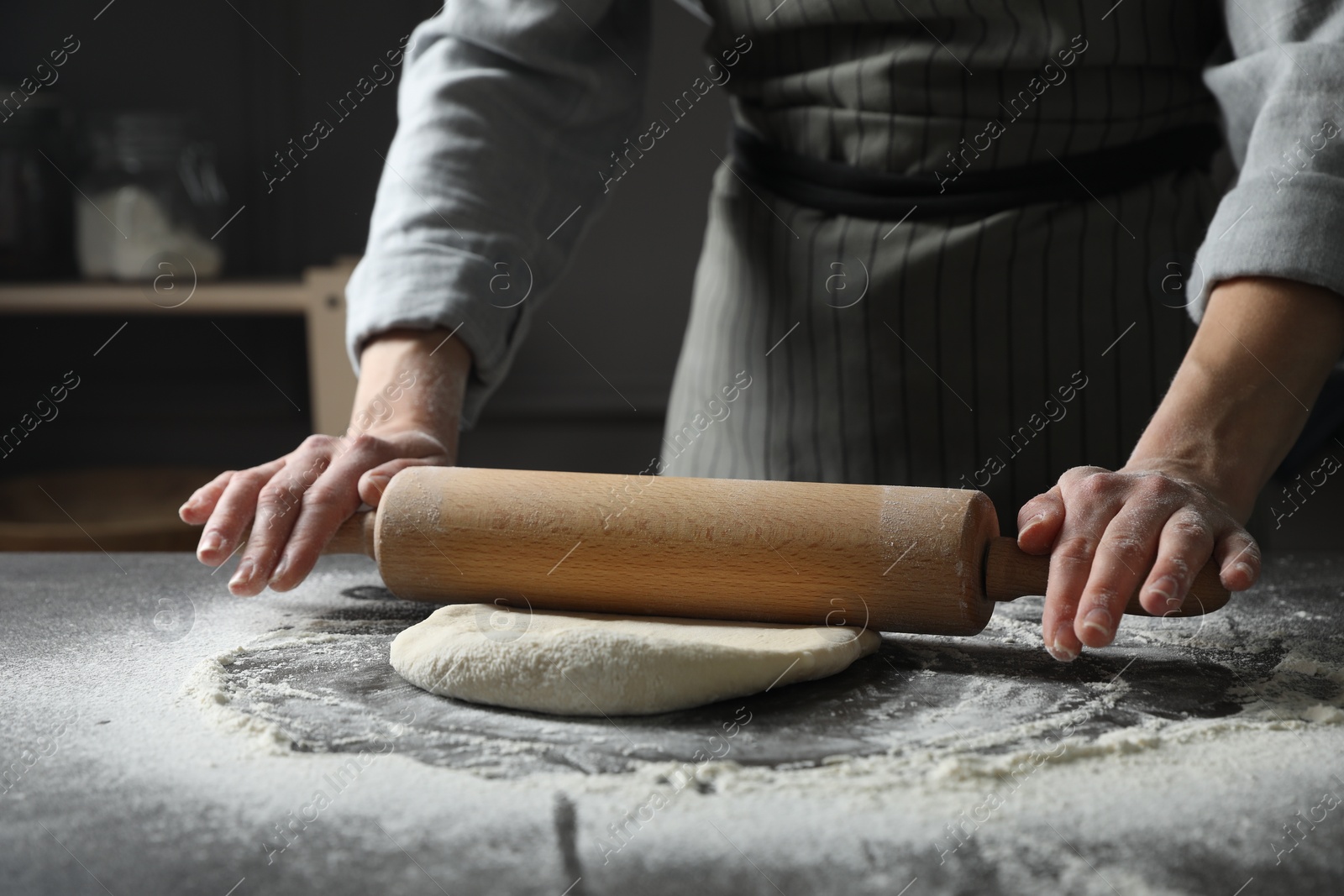 Photo of Woman rolling pizza dough with pin at table, closeup