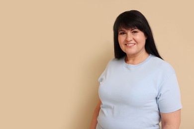 Photo of Beautiful overweight mature woman with charming smile on beige background. Space for text