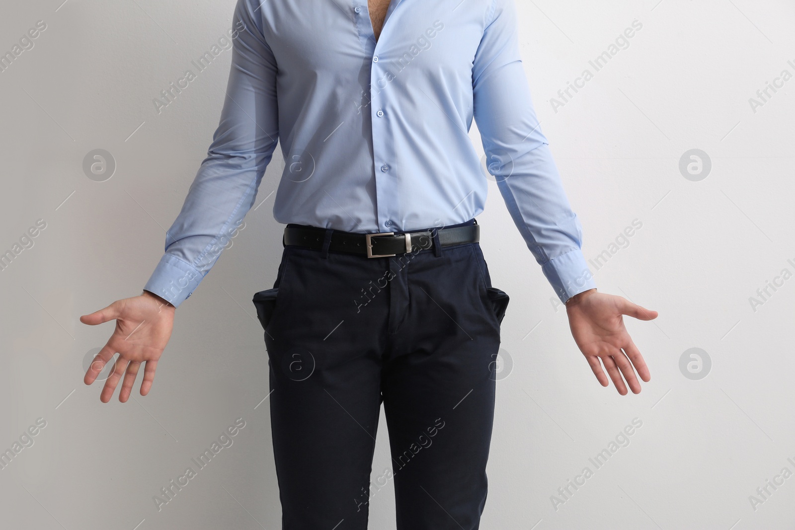 Photo of Businessman showing empty pockets on light background, closeup