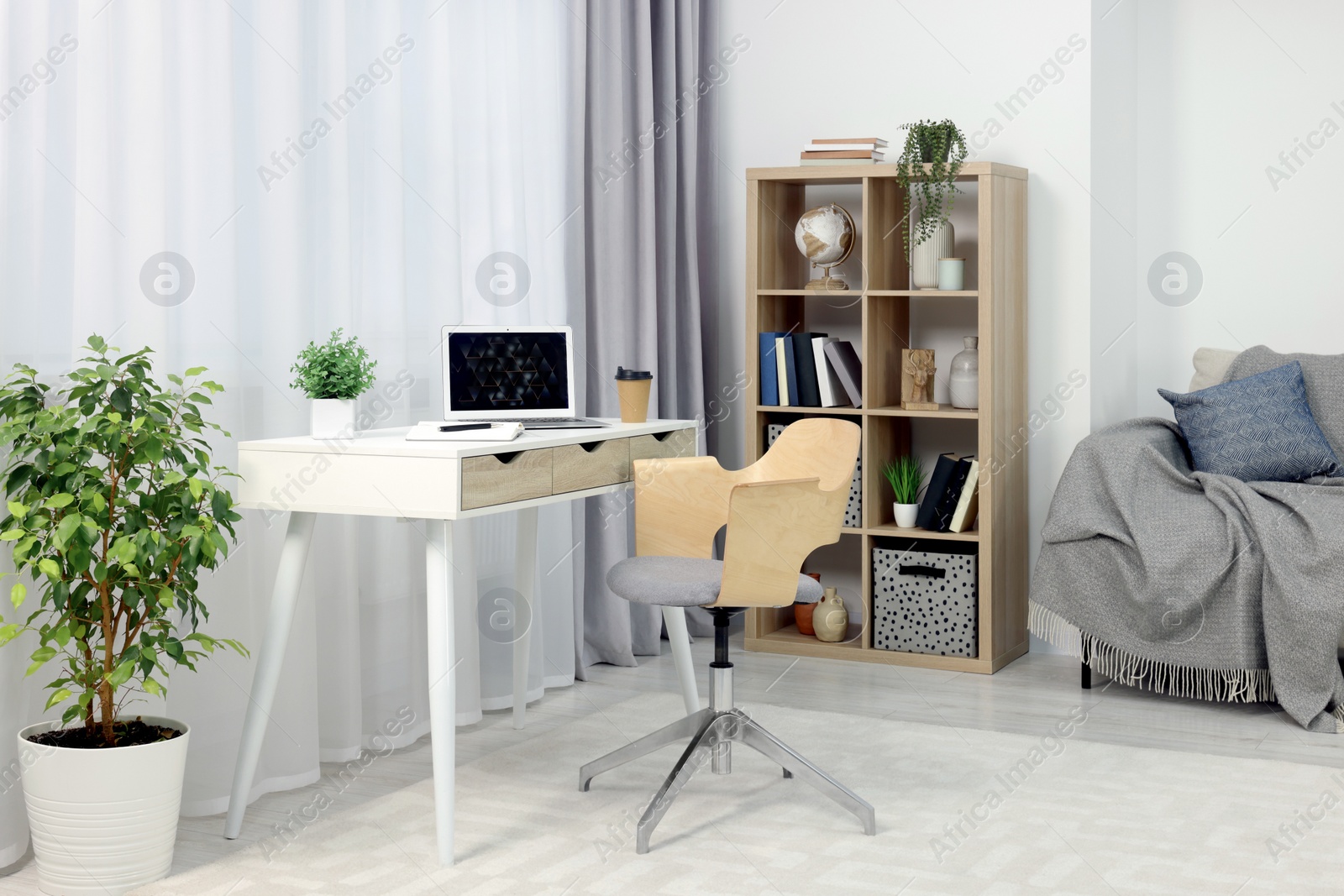 Photo of Workplace with modern laptop on desk and comfortable chair at home