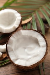 Photo of Ripe coconut with cream on wooden table. Space for text