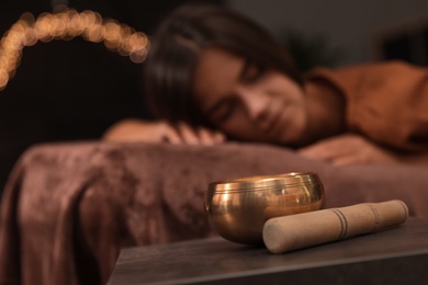 Photo of Woman at healing session in dark room, focus on singing bowl