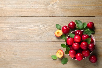 Fresh ripe cherry plums on wooden table, flat lay. Space for text