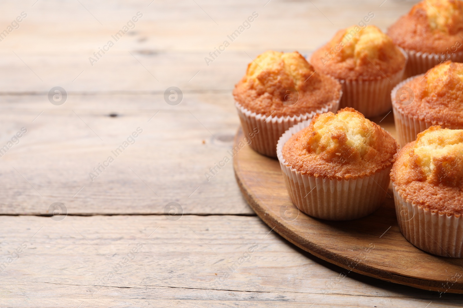 Photo of Delicious sweet muffins on wooden table, closeup. Space for text