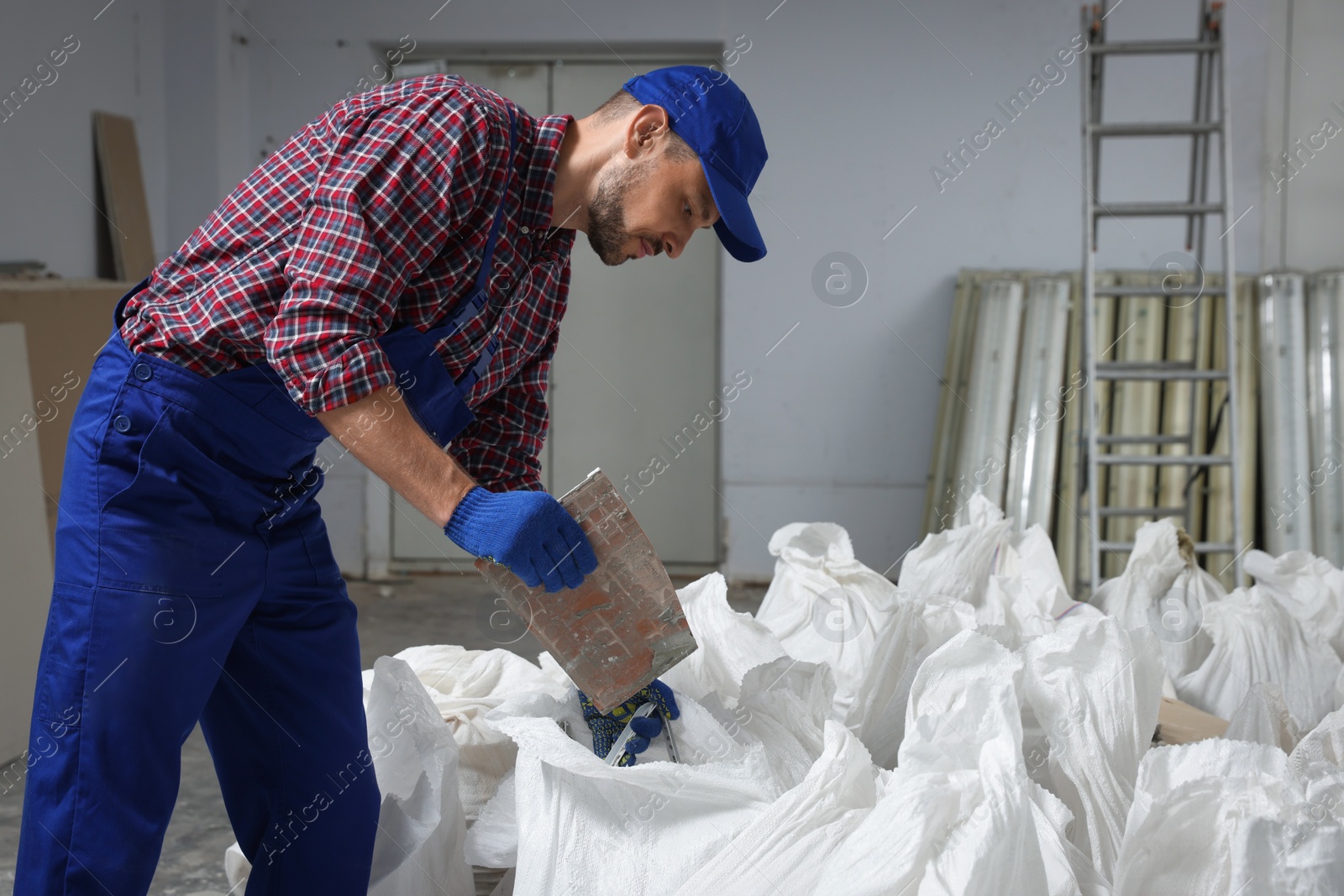 Photo of Construction worker with used building materials in room prepared for renovation