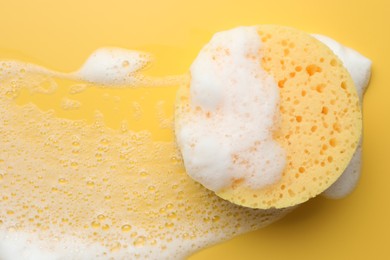 Photo of Sponge with foam on yellow background, top view