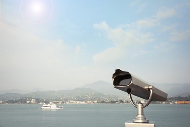 Photo of Metal tower viewer installed near sea, space for text. Mounted binoculars