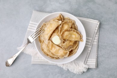 Photo of Delicious dumplings (varenyky) with cottage cheese and butter served on light grey table, top view