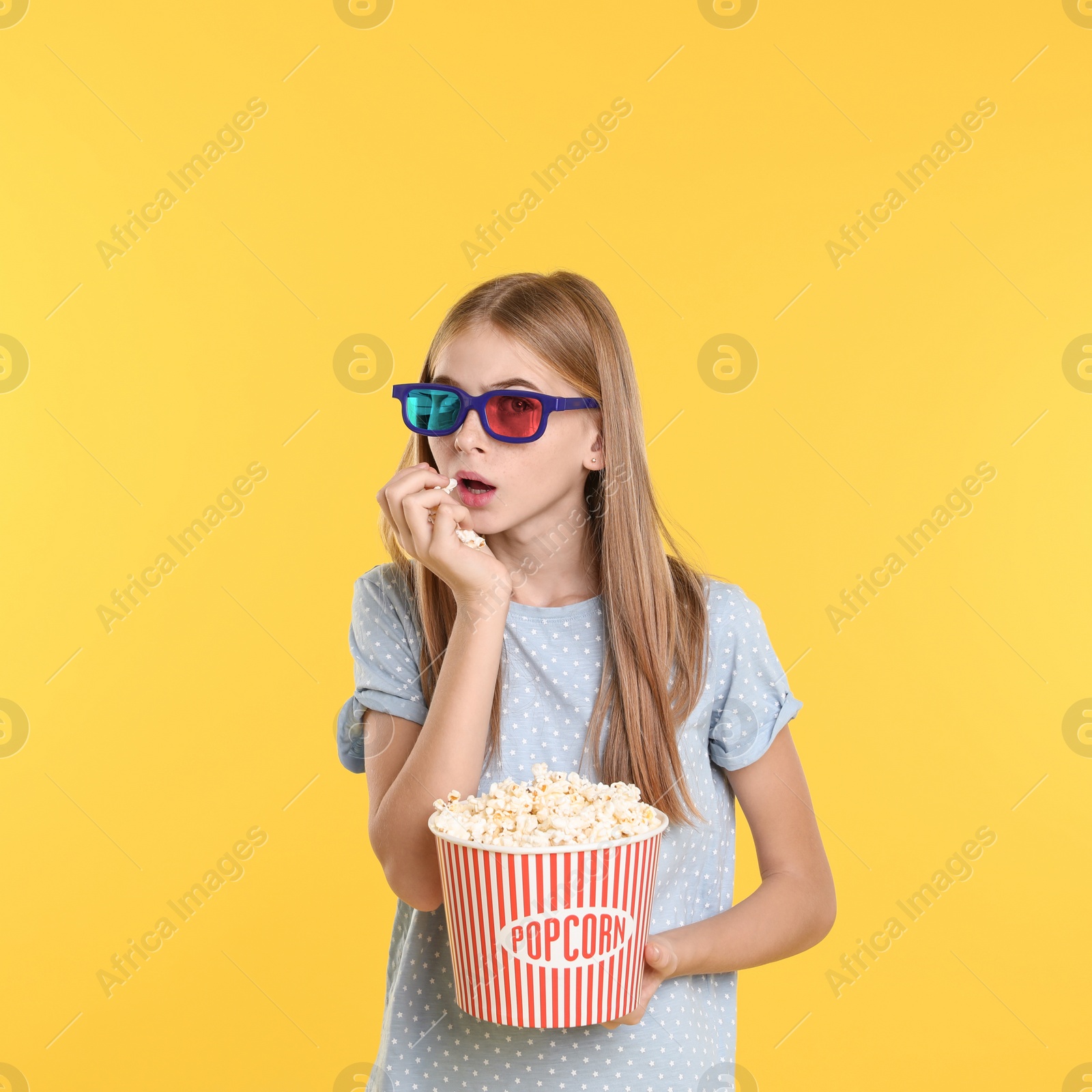 Photo of Emotional teenage girl with 3D glasses and popcorn during cinema show on color background