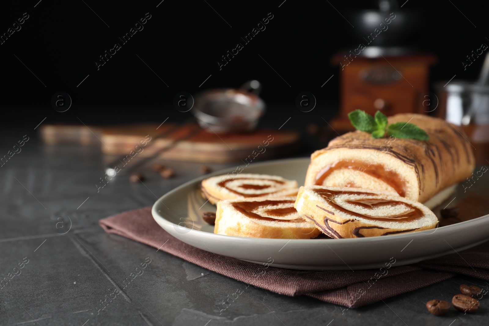 Photo of Tasty cake roll with jam and mint on grey table. Space for text