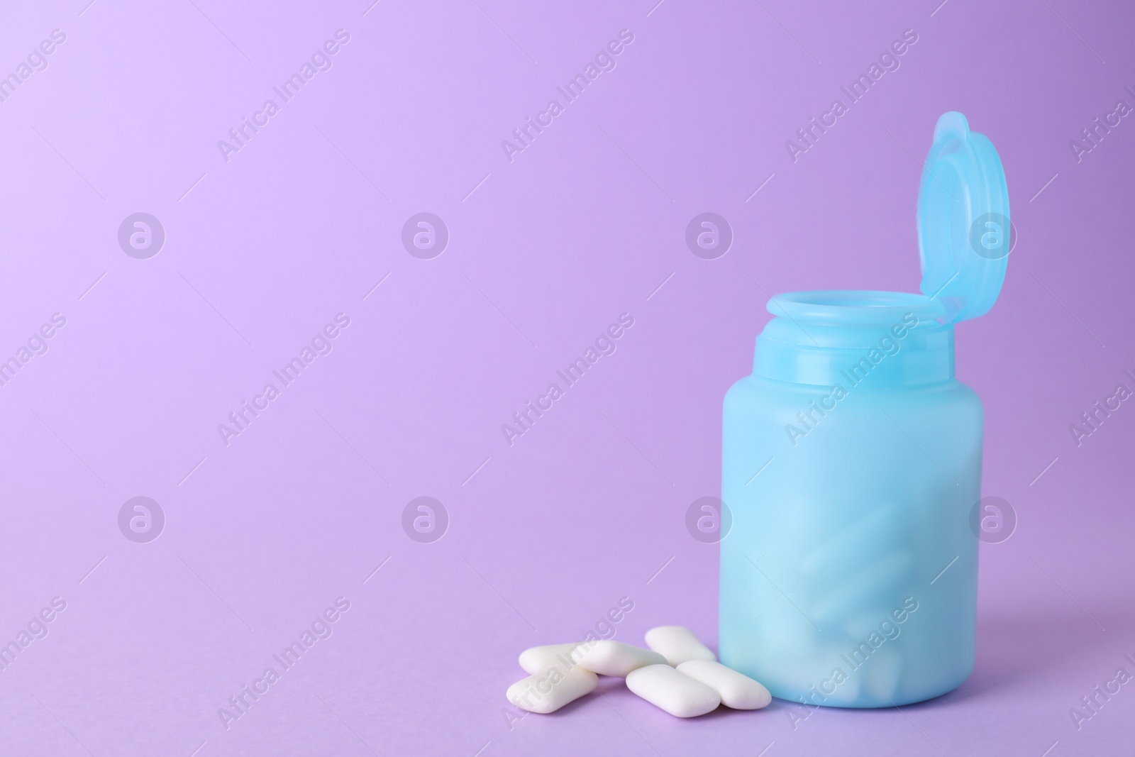 Photo of Jar with chewing gums on lilac background. Space for text