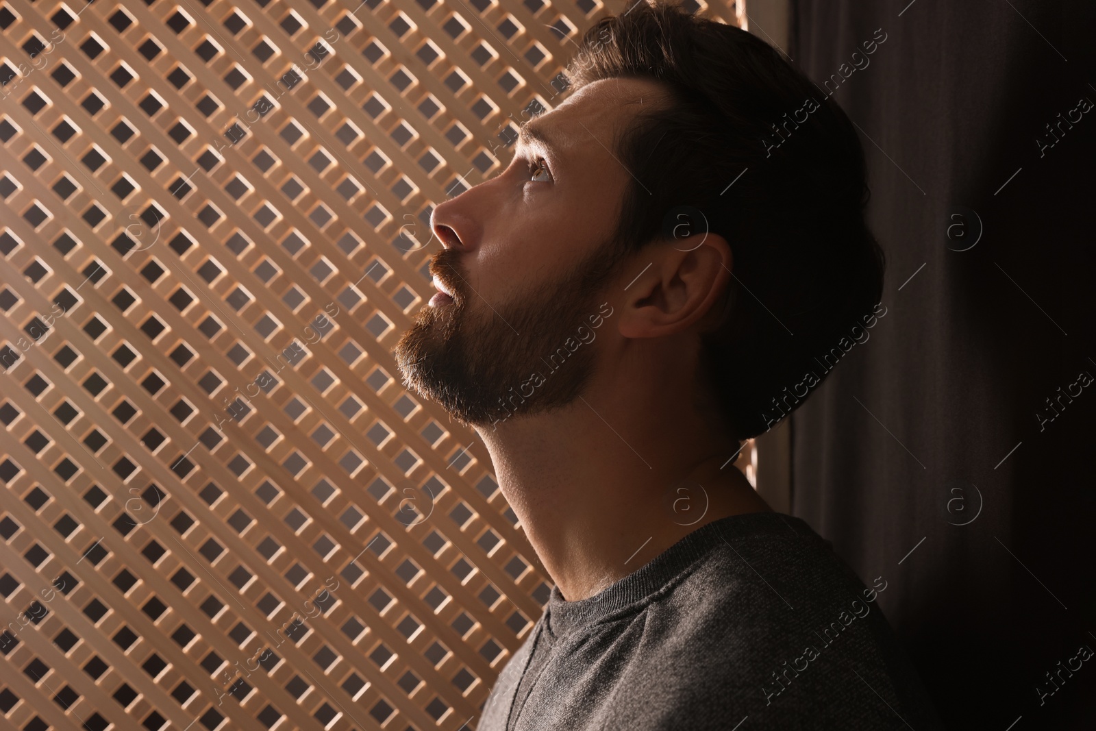 Photo of Man listening to priest during confession in booth, space for text