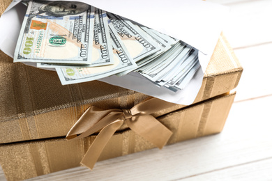 Photo of Gift box with dollar bills on white wooden table