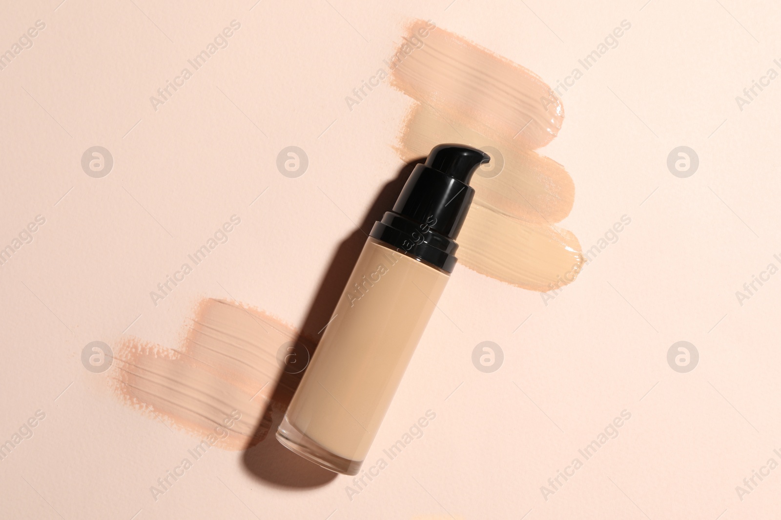 Photo of Liquid foundation and swatches on beige background, top view