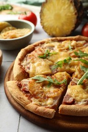 Photo of Delicious cut pineapple pizza with arugula on light grey table, closeup