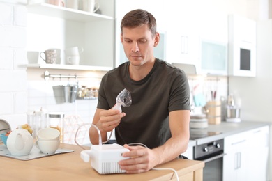 Man using asthma machine at table in kitchen