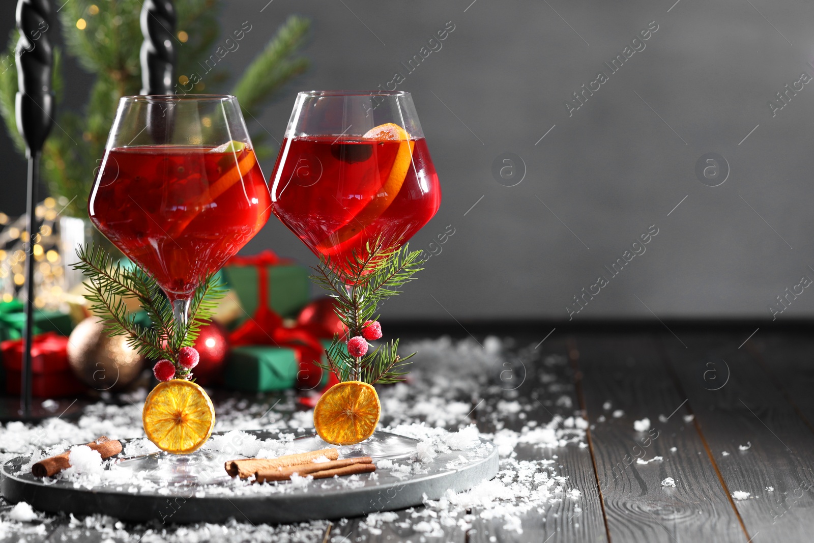 Photo of Christmas Sangria cocktail in glasses and snow on dark wooden table, space for text