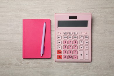 Calculator and office stationery on light wooden table, flat lay