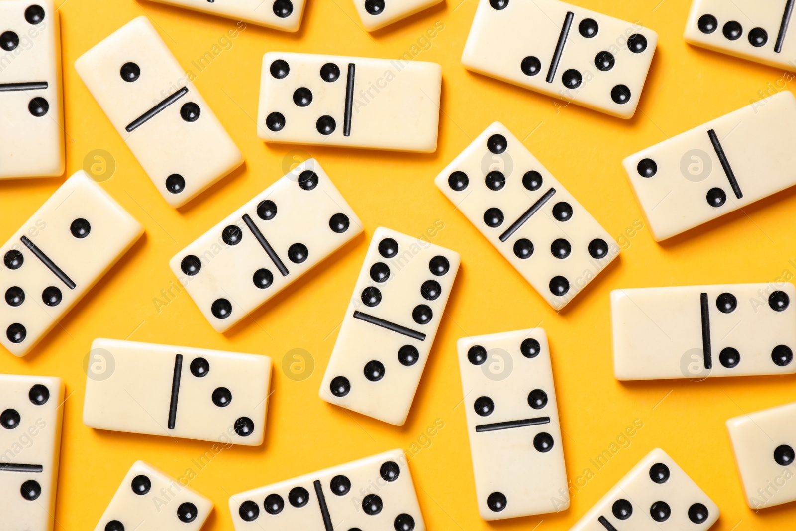 Photo of Classic domino tiles on yellow background, flat lay