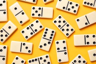 Photo of Classic domino tiles on yellow background, flat lay