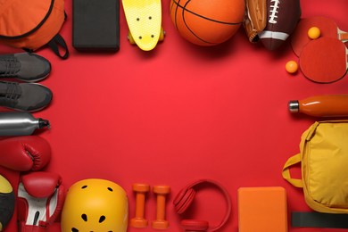 Photo of Frame made of different sports equipment on red background, flat lay. Space for text
