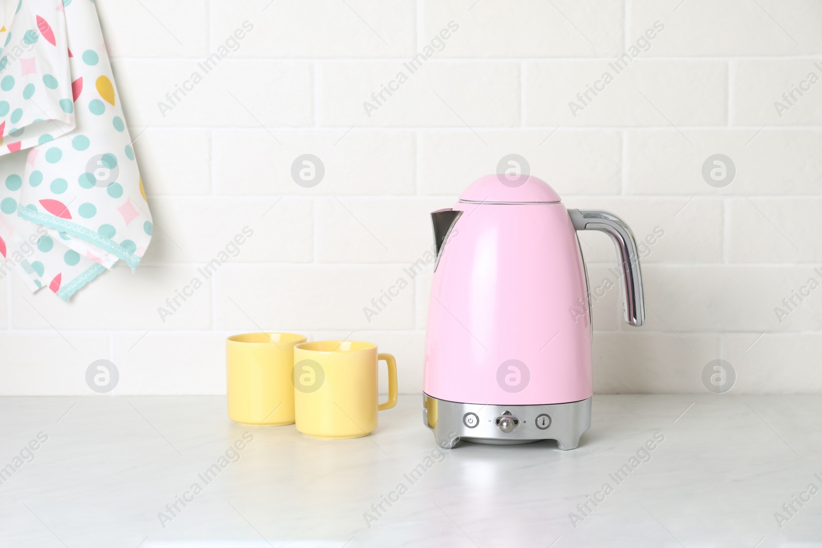 Photo of Modern electric kettle and cups on counter in kitchen