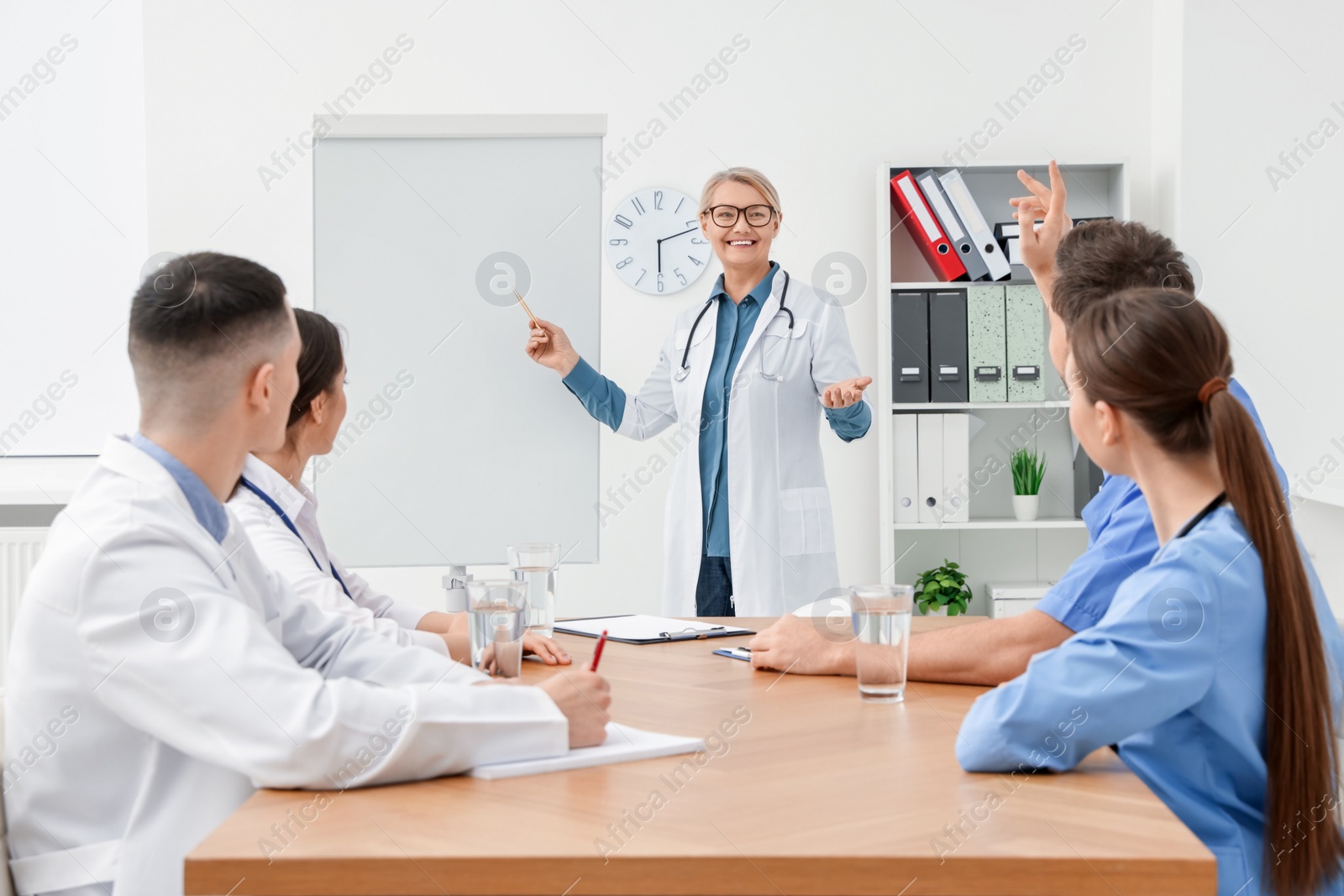 Photo of Doctor giving lecture near flipchart in conference room