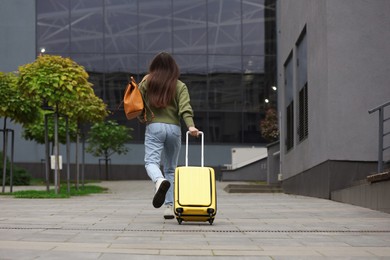 Photo of Being late. Woman with backpack and suitcase running outdoors, low angle view