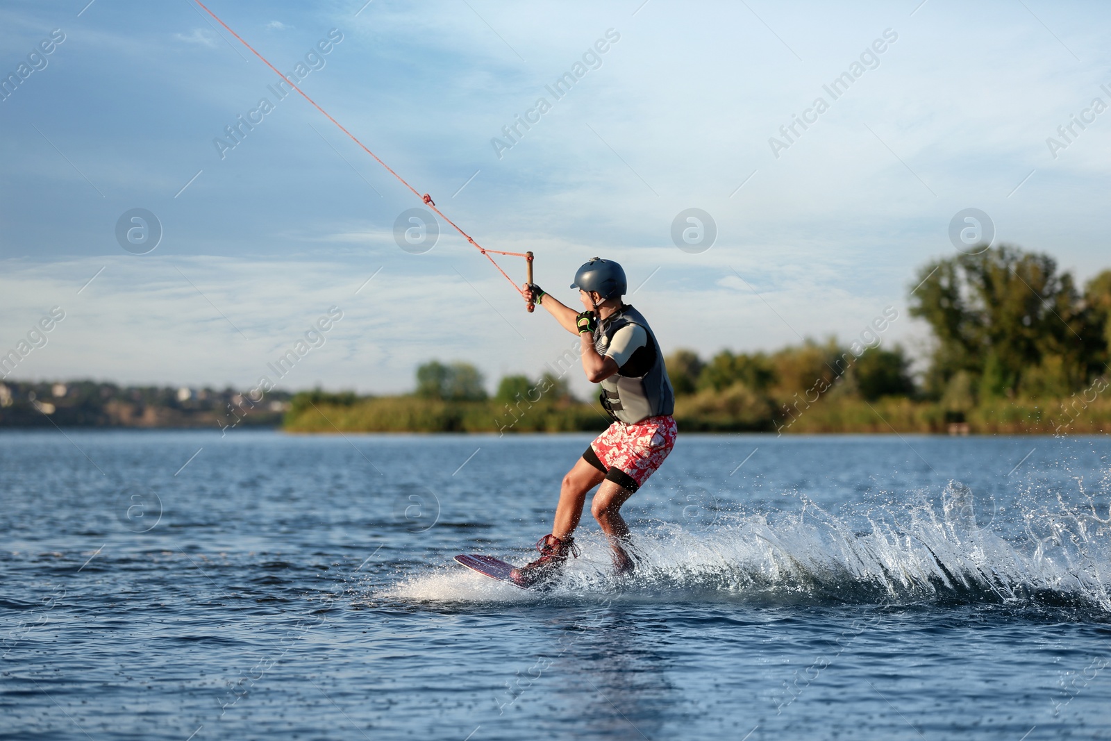 Photo of Teenage boy wakeboarding on river. Extreme water sport