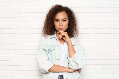 Young African-American woman with beautiful face near white brick wall