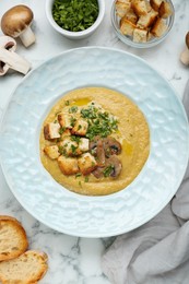Photo of Delicious cream soup with mushrooms and croutons on white marble table, flat lay