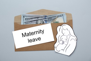 Photo of Note with words Maternity Leave, envelope, dollar banknotes, paper cutout of mother and child on light grey background, top view