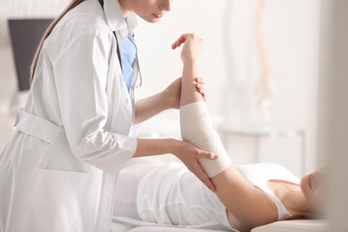 Female orthopedist examining patient's elbow in clinic, closeup