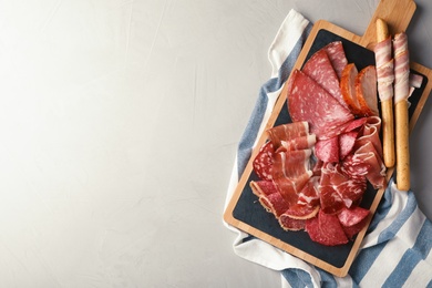 Photo of Different meat delicacies served on gray table, top view. Space for text