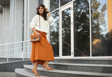 Photo of Young woman with stylish brown bag on stairs near building