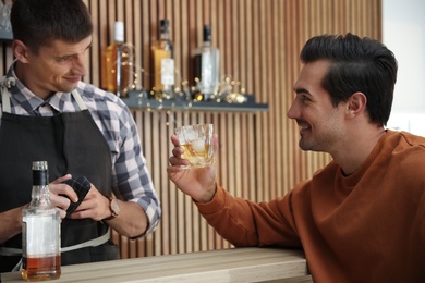 Photo of Young man with glass of whiskey in bar