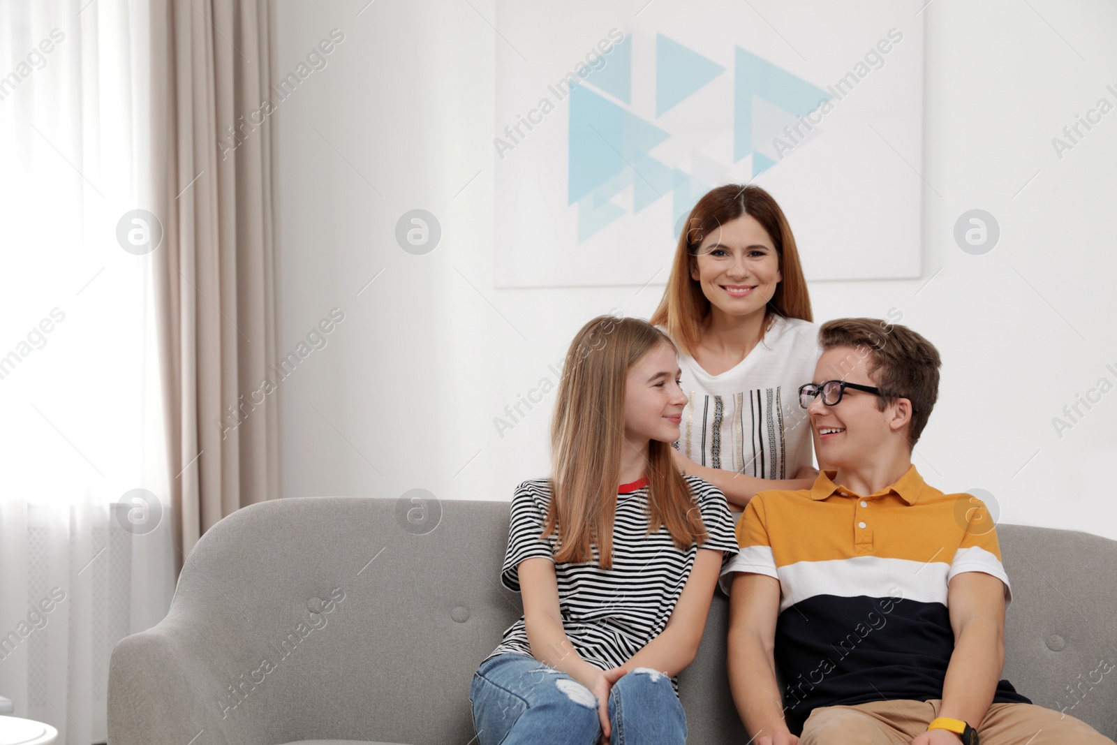 Photo of Happy mother with her teenager daughter and son at home