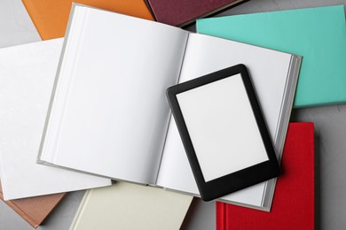 Photo of Portable e-book reader on hardcover books on grey textured table, flat lay