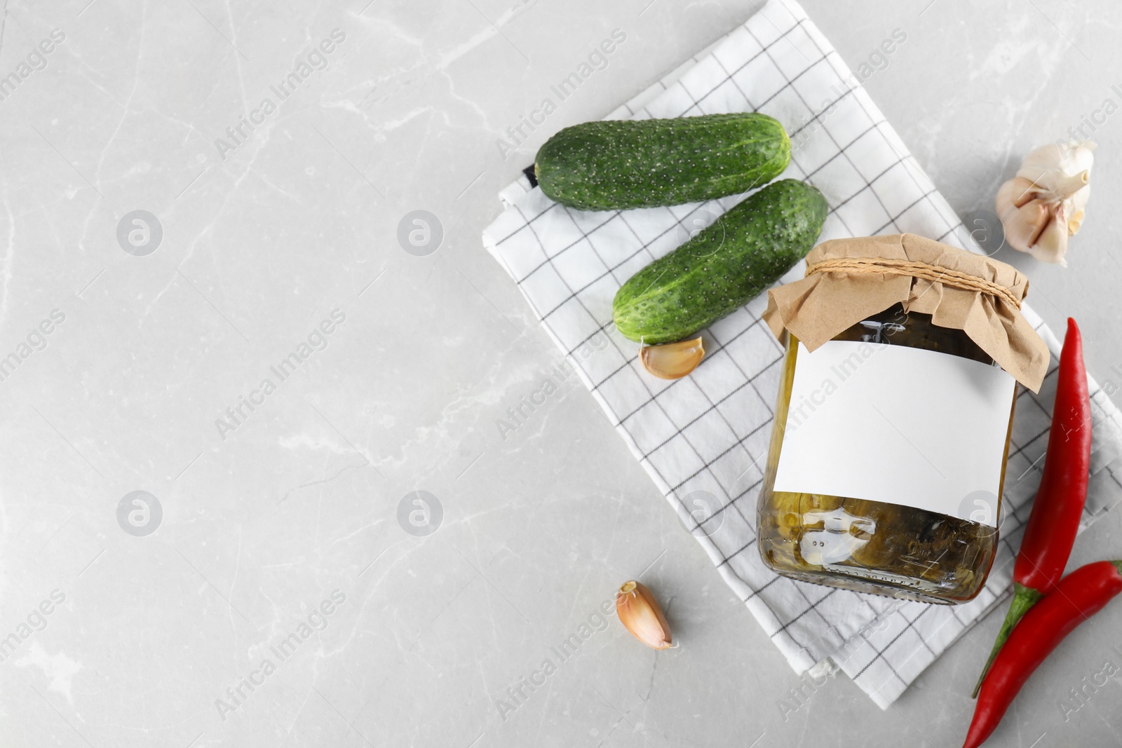 Photo of Flat lay composition with jar of pickled cucumbers on light table, space for text