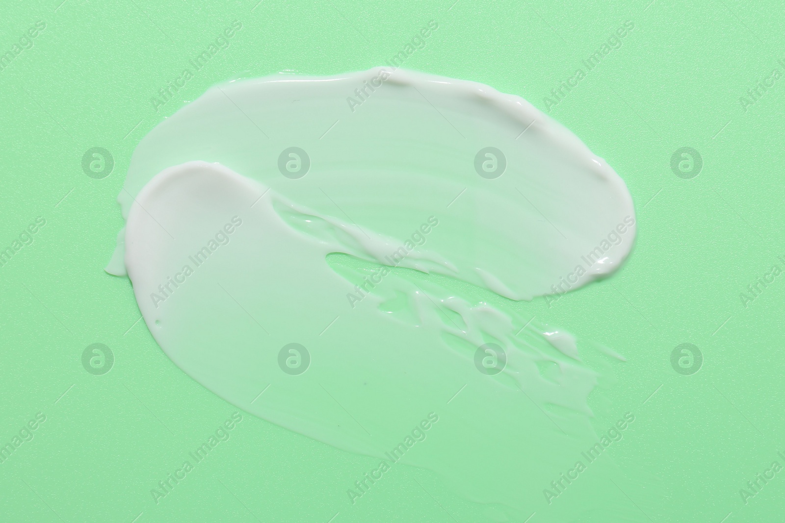 Photo of Samples of face cream on green background, top view