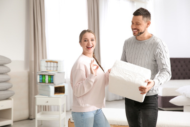 Photo of Happy couple choosing mattress in furniture store