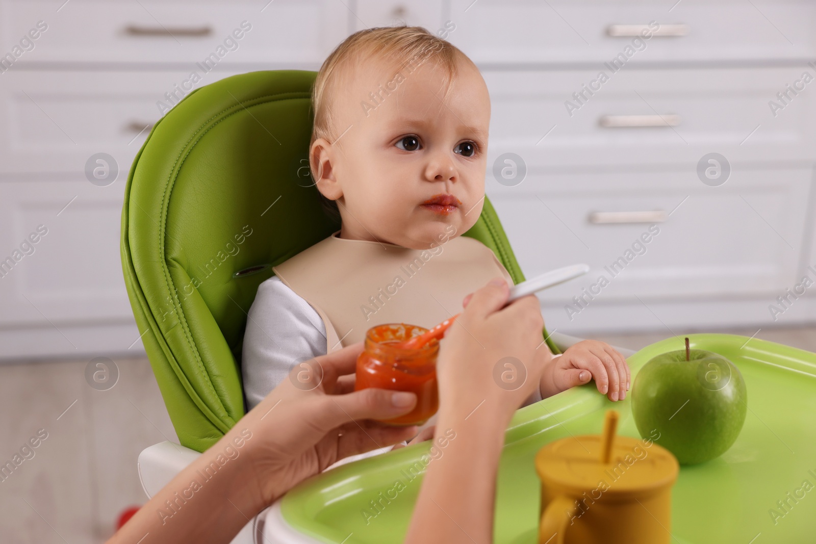 Photo of Mother feeding her cute little baby with healthy food at home