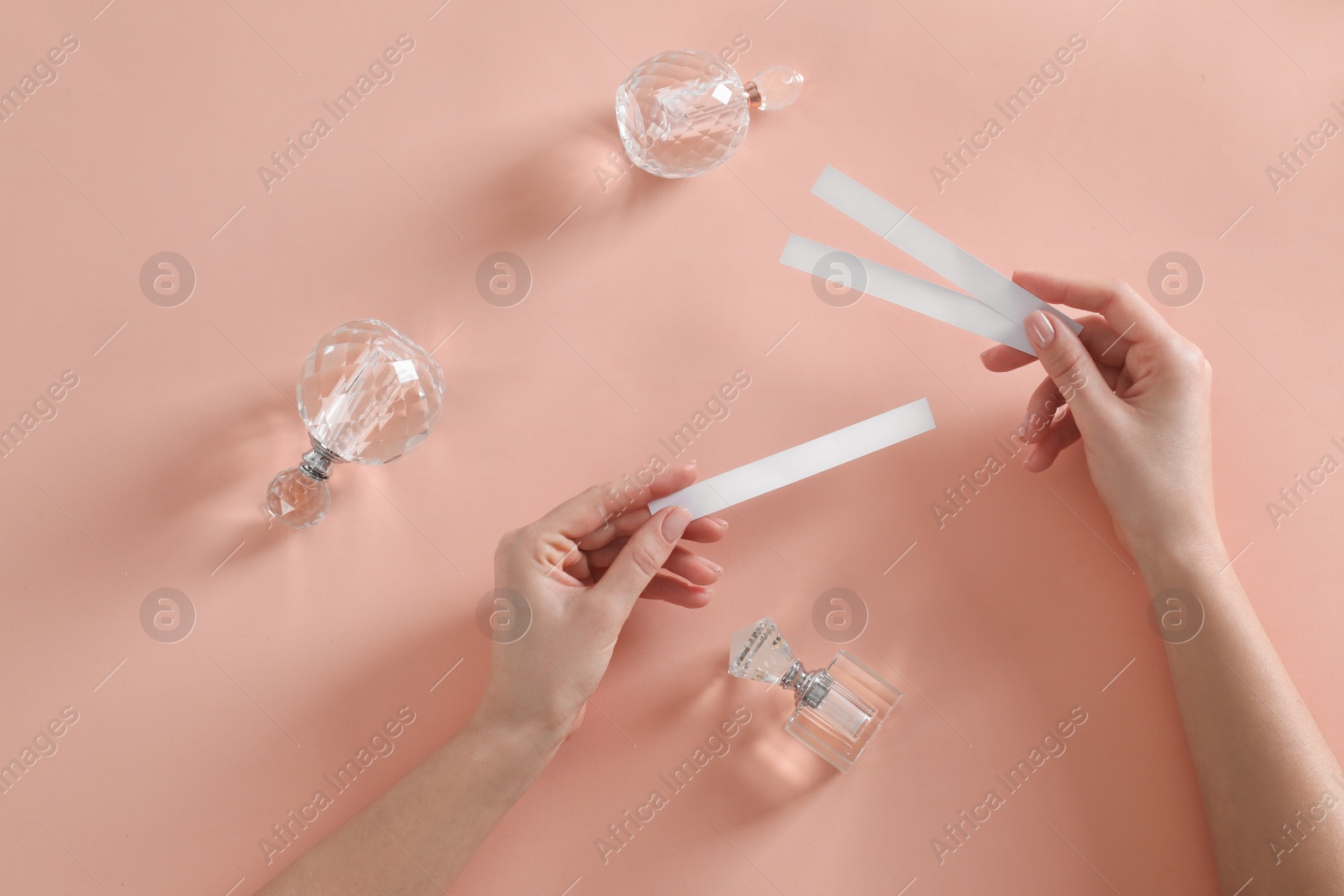 Photo of Woman with perfume testing stripes on peach background, top view