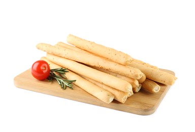 Photo of Wooden board with delicious grissini, rosemary and tomato on white background