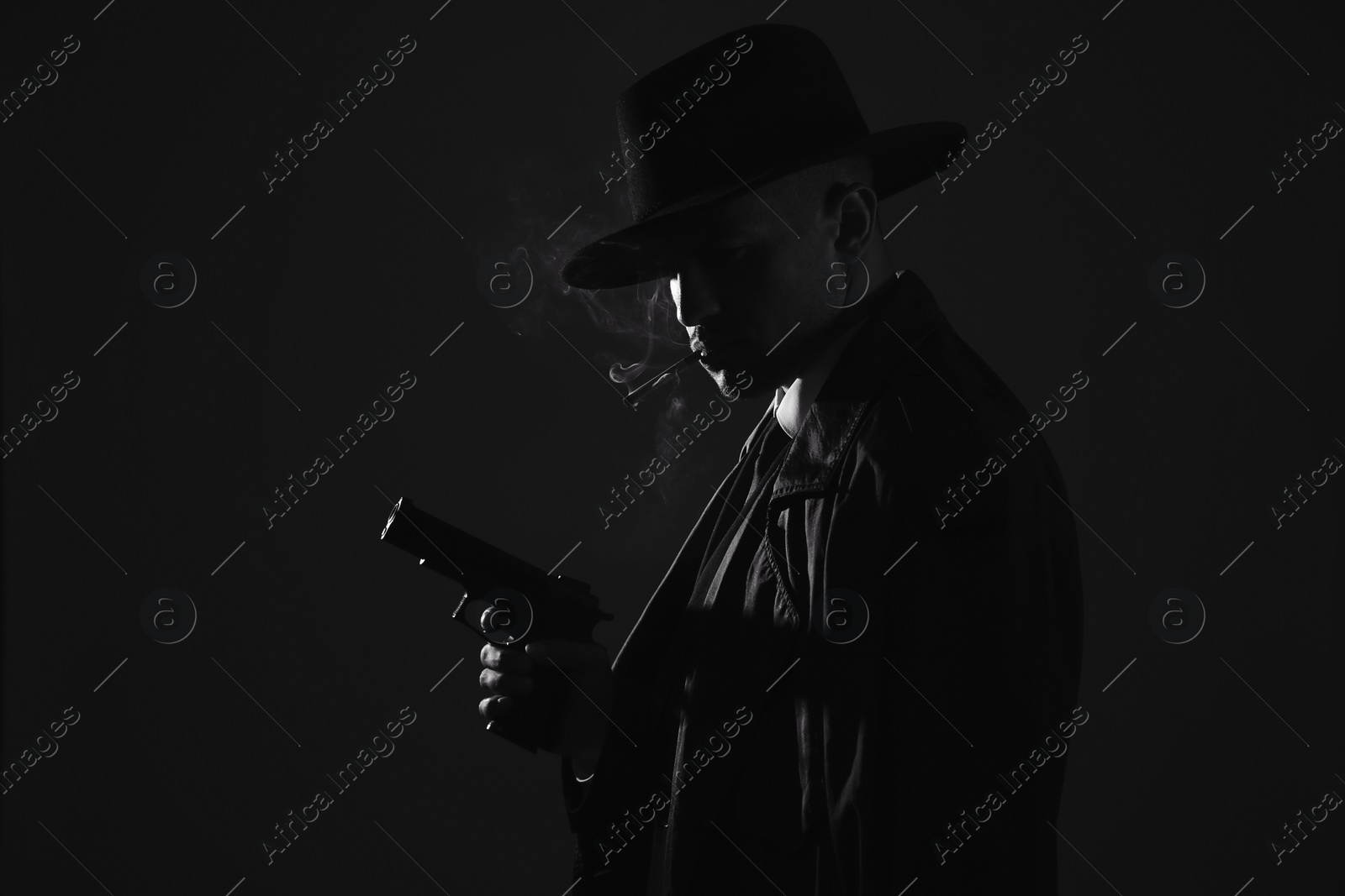 Photo of Old fashioned detective with gun smoking cigarette on dark background, black and white effect