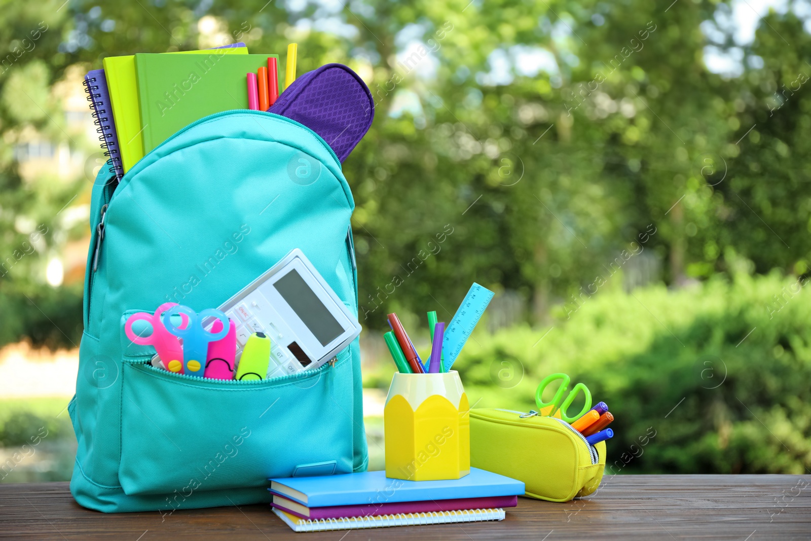 Photo of Bright backpack and school stationery on table outdoors, space for text