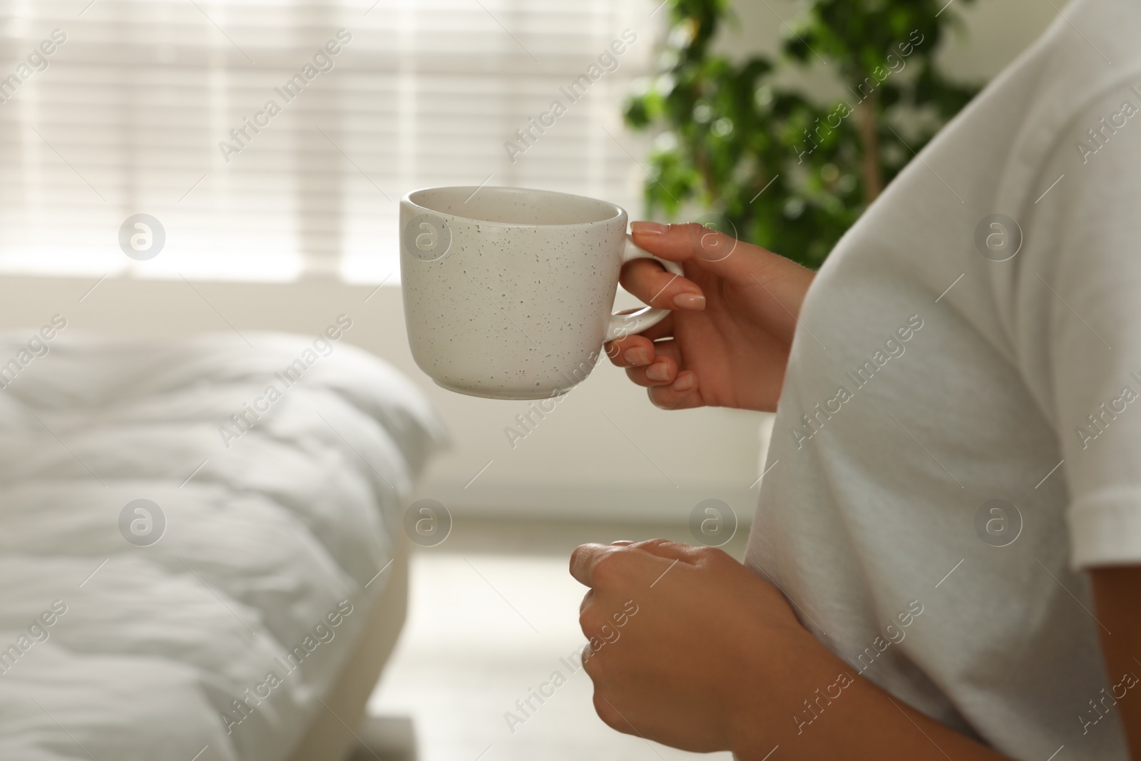 Photo of Woman with white cup in bedroom, closeup