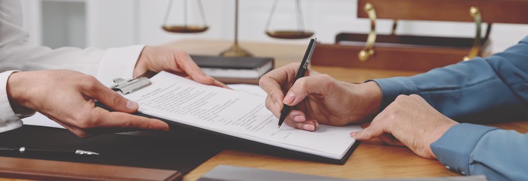 Image of Lawyer working with client at wooden table in office, closeup. Banner design